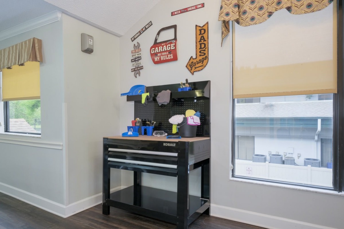 A children's play area featuring a toy workbench with colorful tools and playful wall decorations.