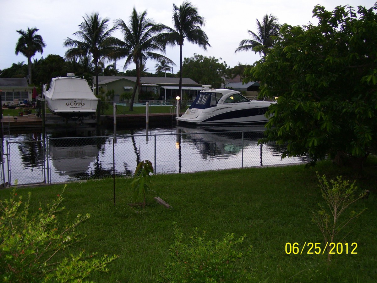 A serene canal view with boats docked and palm trees in the background.