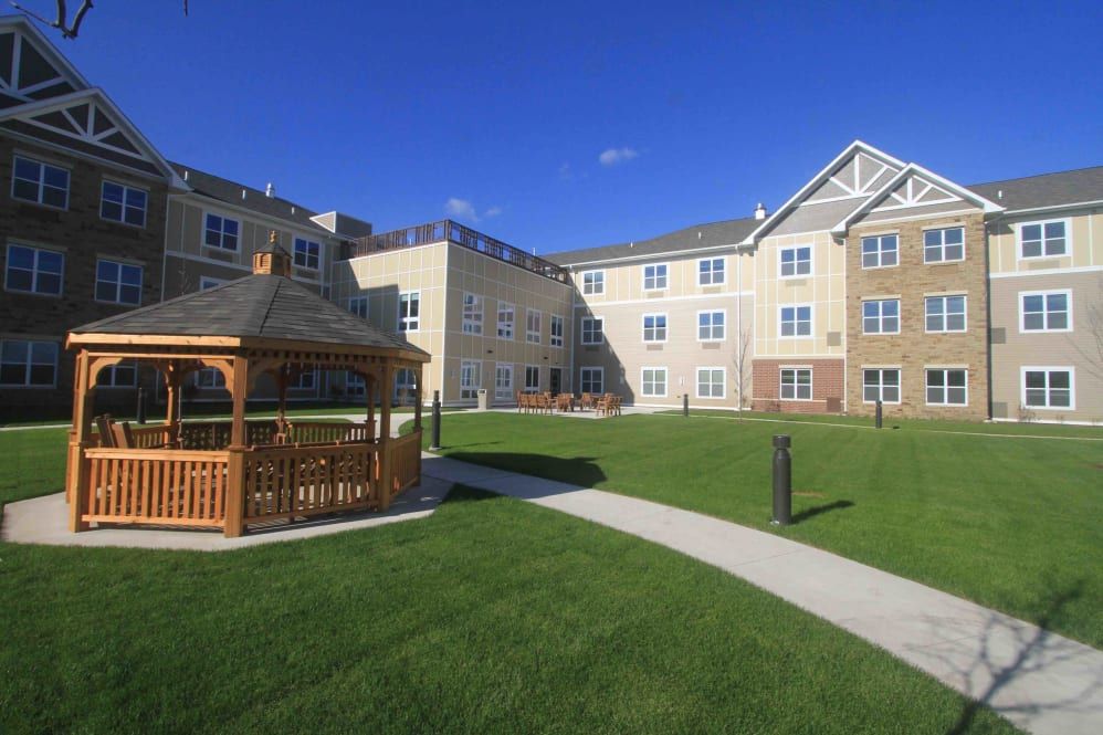 A residential apartment complex with a well-maintained lawn and a gazebo under a clear blue sky.