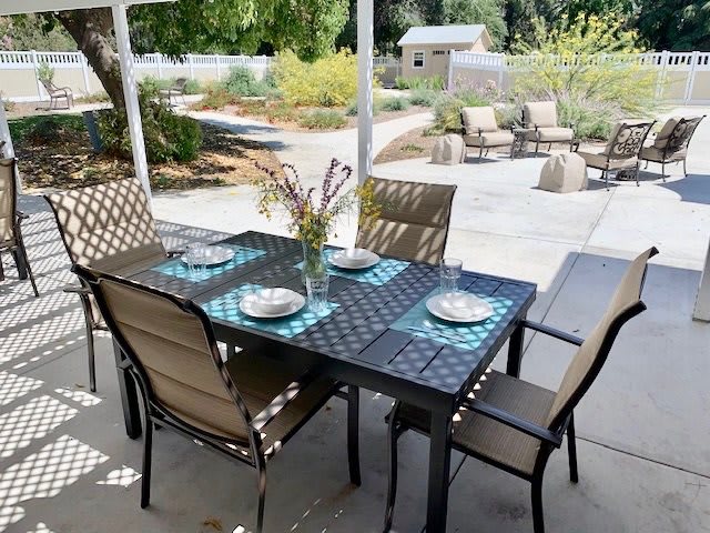 A cozy outdoor patio dining area with a set table and garden view.