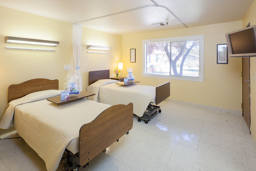 A well-lit hospital patient room featuring two beds, designed for comfort and care.