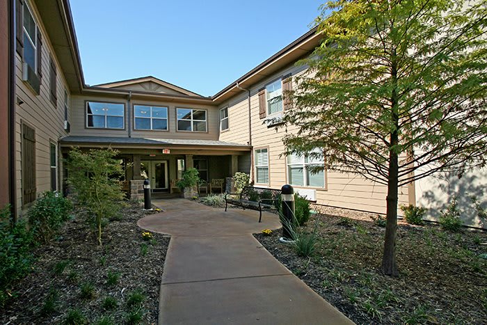 A residential building with a landscaped entrance and a winding pathway.