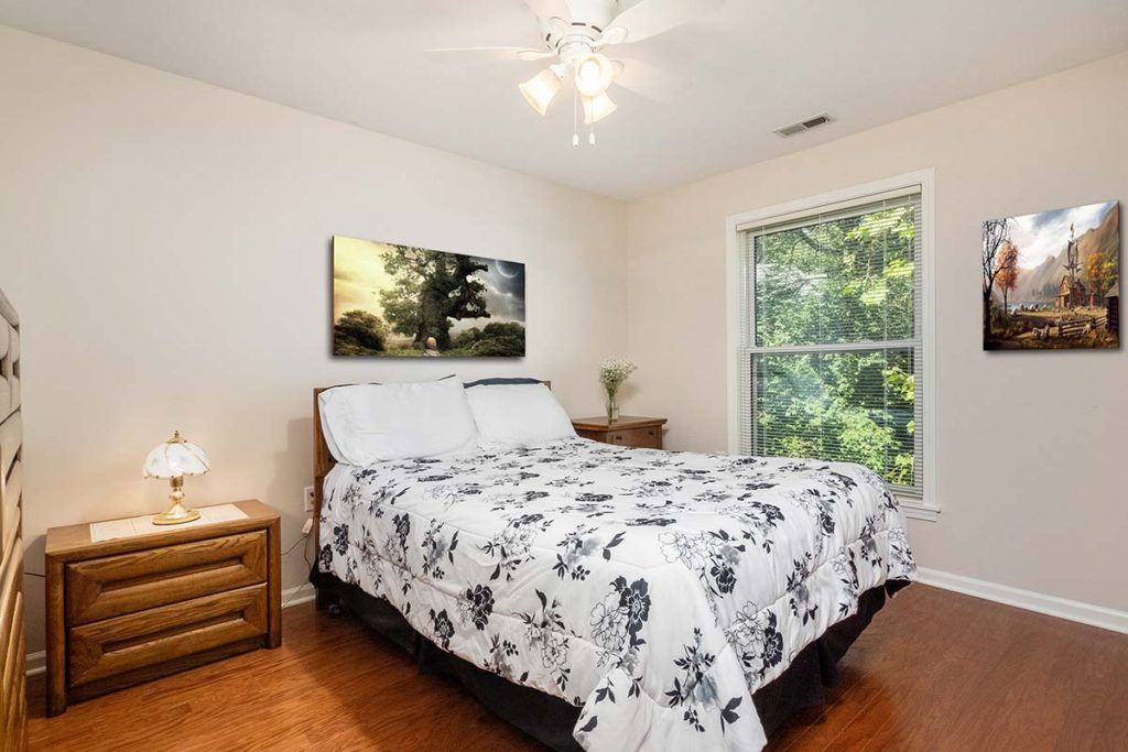 A cozy bedroom with a large window offering a view of greenery.