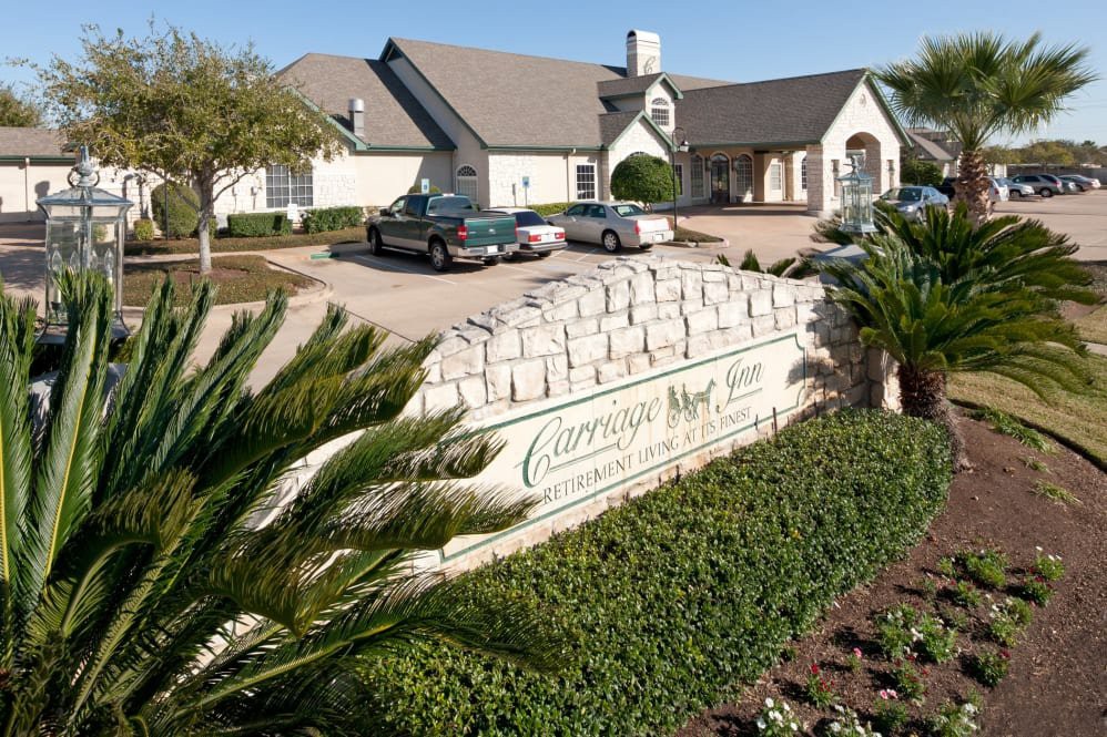A retirement home entrance with a landscaped garden and parked cars.
