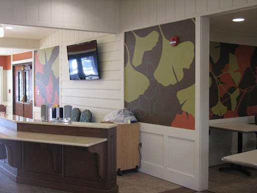 A modern office reception area featuring colorful wall art and a television.