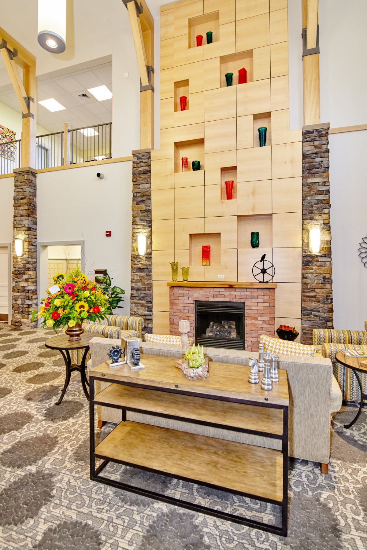 A modern lobby featuring a central fireplace, colorful artwork, and elegant decor.