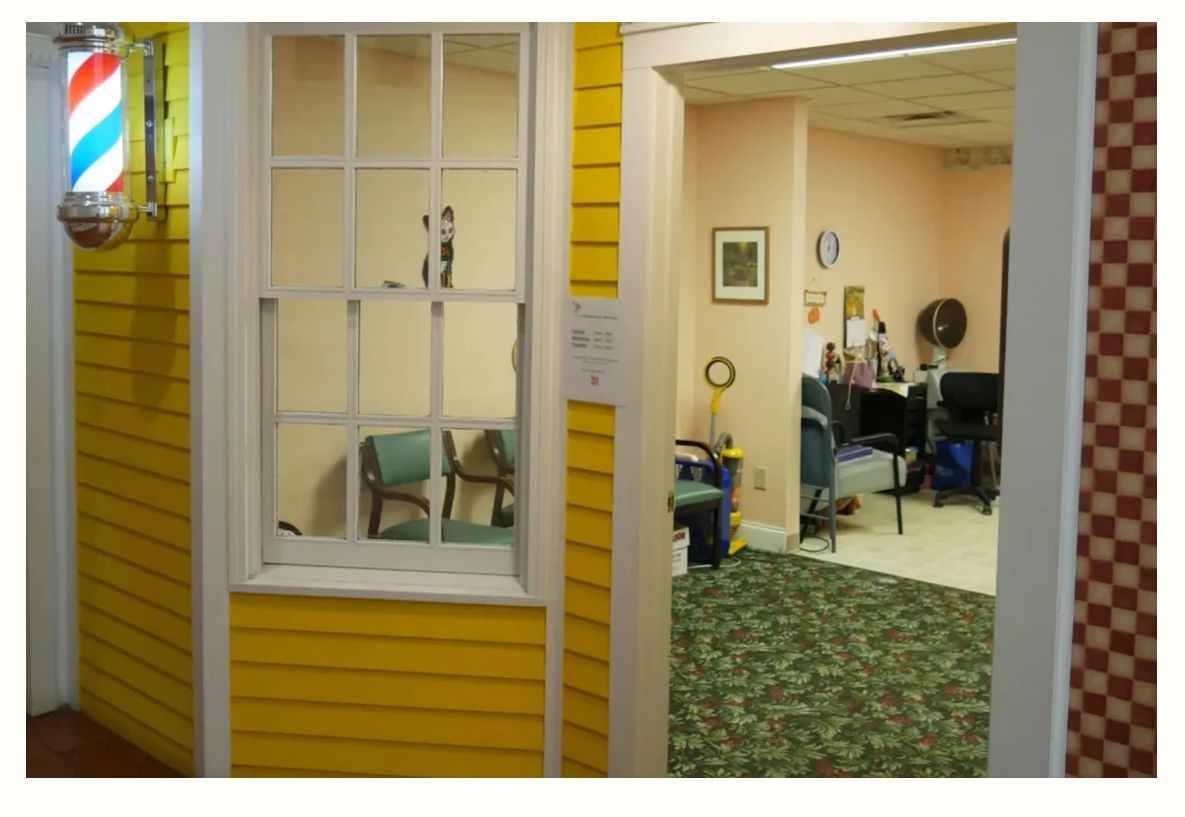 A view of a hair salon with a waiting area featuring chairs and a window set into a yellow wall.