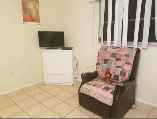 A cozy corner of a living room featuring a comfortable chair, a television, and a dresser.
