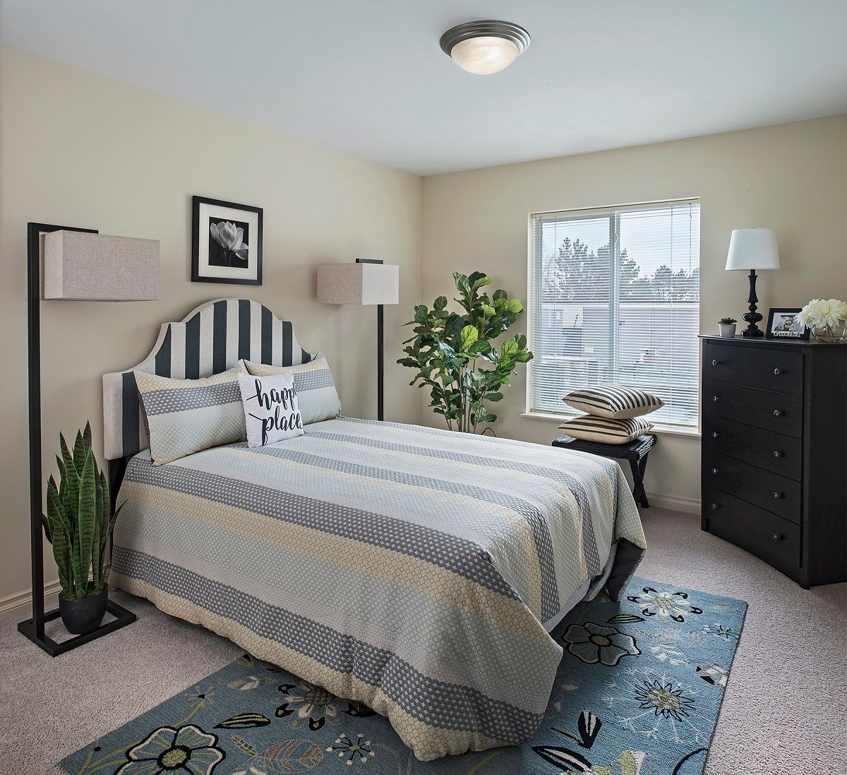 A cozy bedroom with a striped bedspread and decorative plants.