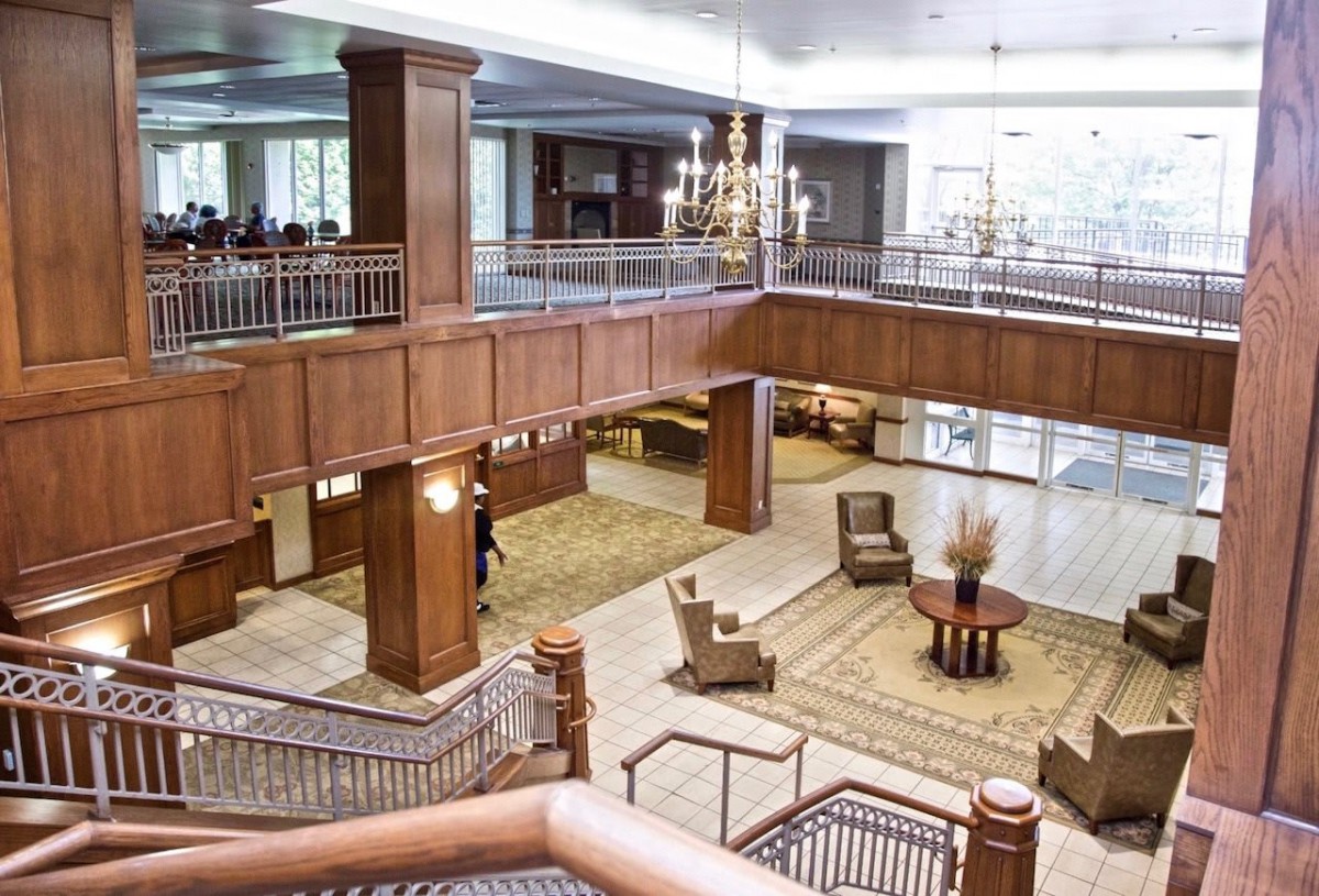 Spacious hotel lobby with elegant staircase and seating area.