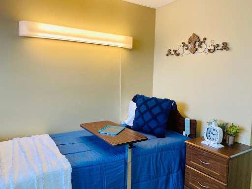 A cozy bedroom setup featuring two beds with blue bedding, a wooden dresser, and warm lighting.
