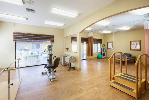 A spacious physical therapy room equipped with various exercise machines and open areas for rehabilitation activities.