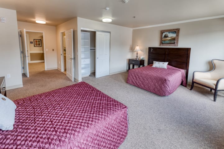 A spacious hotel room with two double beds and a simple interior design.