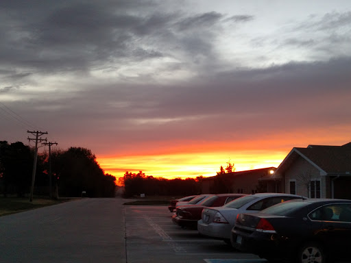 A beautiful sunset paints the sky with vibrant colors, viewed from a quiet parking lot.