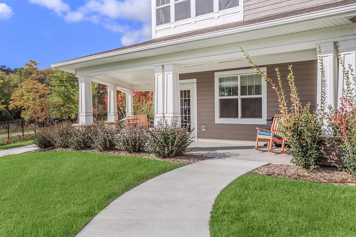 A charming suburban house with a welcoming front porch and a neatly manicured lawn.