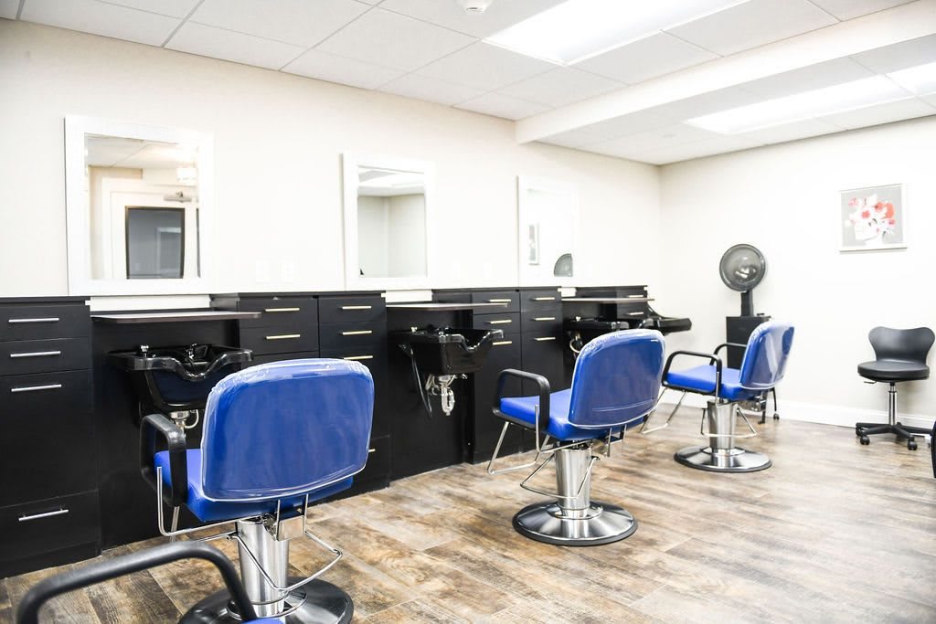 A modern hair salon with blue barber chairs and styling stations.
