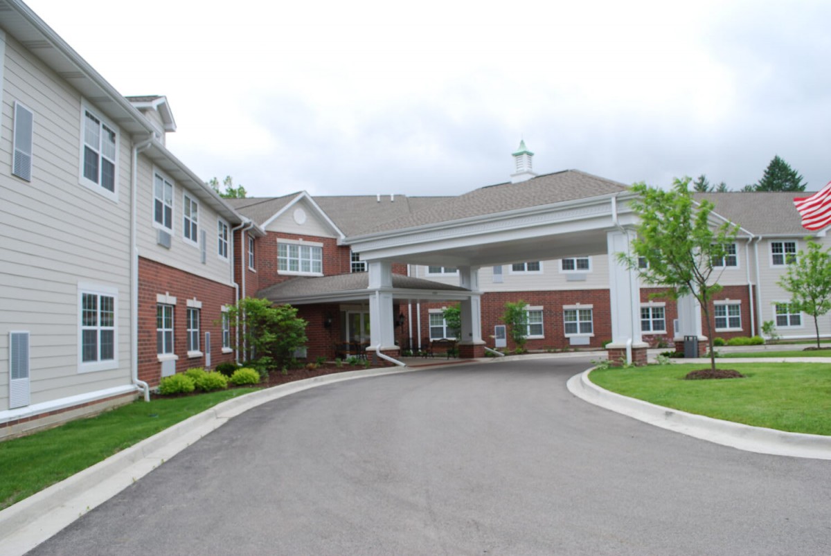 A large residential building with a covered entrance and landscaped surroundings.