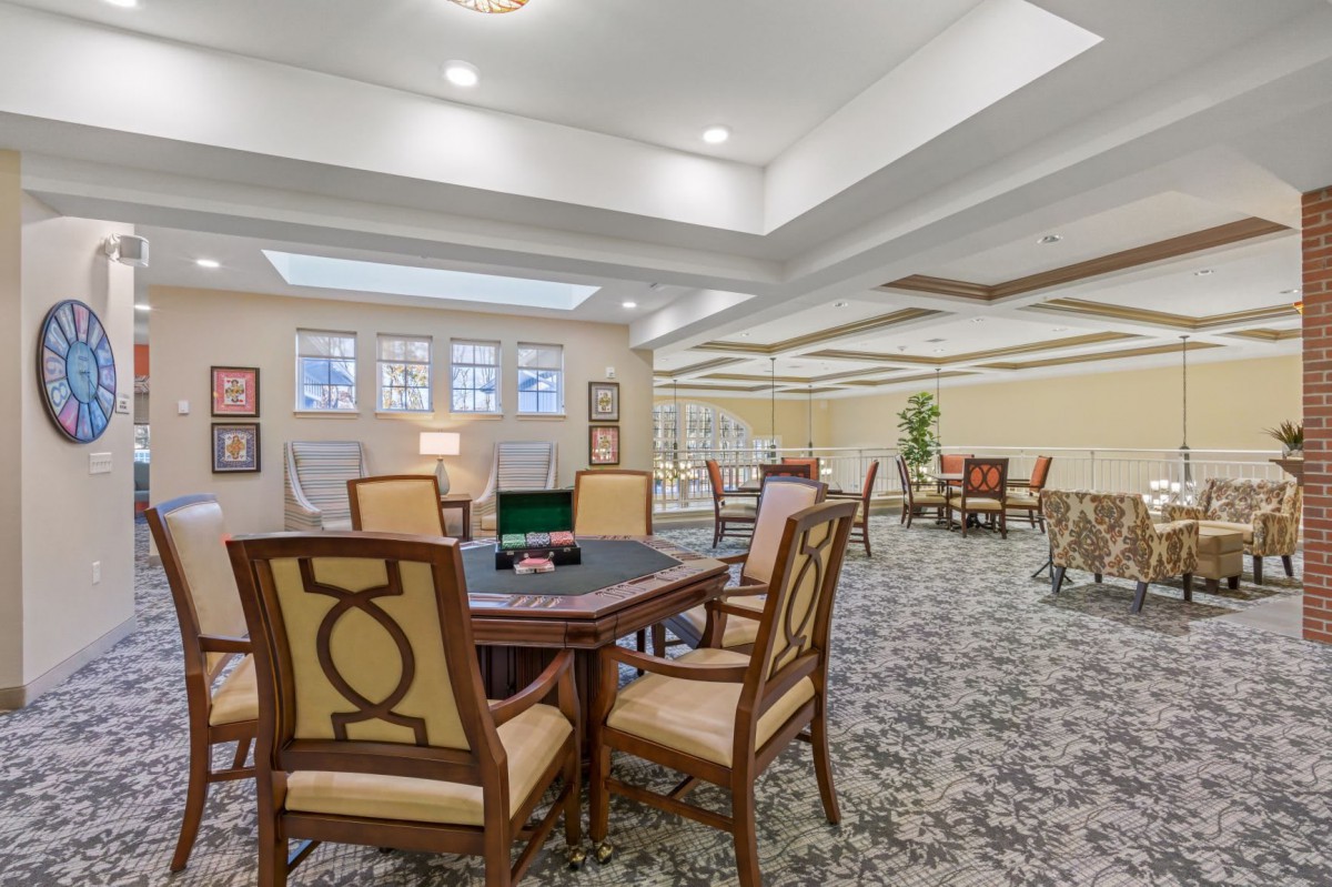 A spacious lobby area with multiple tables and chairs, featuring elegant decor and soft lighting.