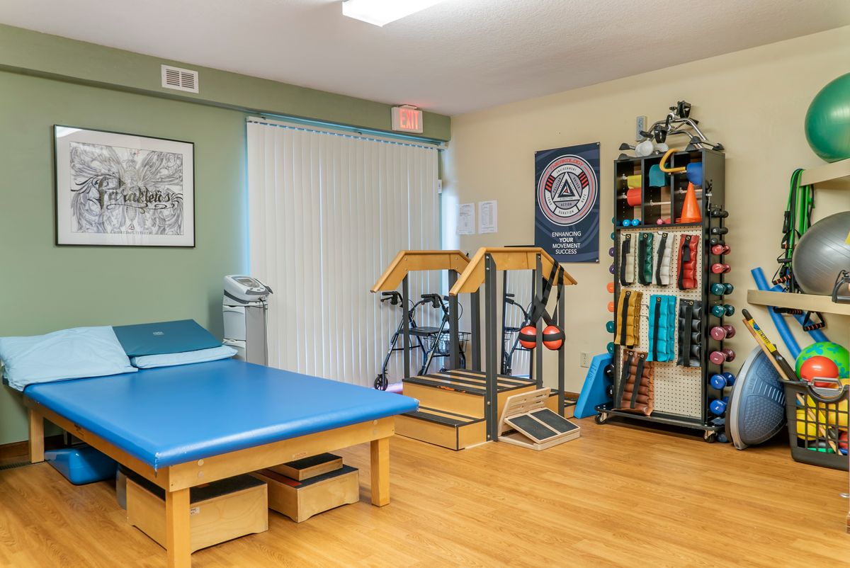 A physical therapy room equipped with a treatment bed, exercise machine, and various therapy tools.