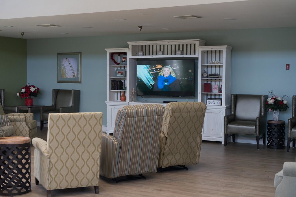 A cozy seating area with patterned chairs facing a television, surrounded by shelves.