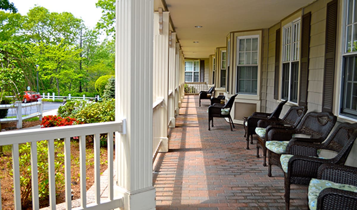 A peaceful porch with chairs and a view of lush greenery.