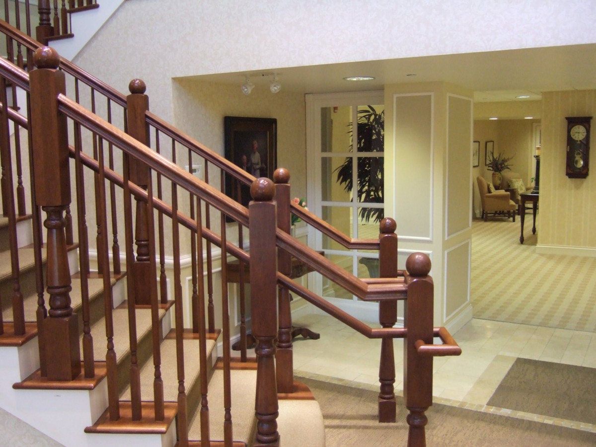 A wooden staircase with detailed railings inside a well-lit hallway.