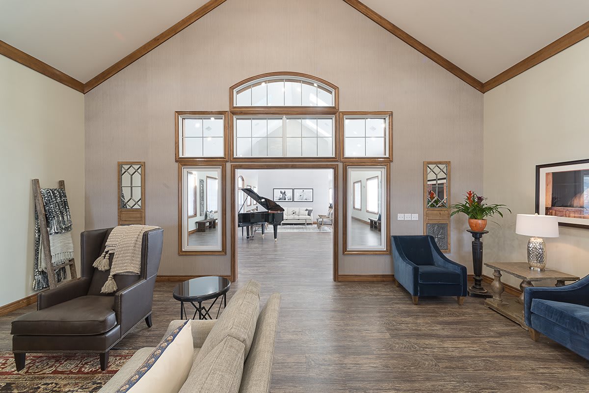 A spacious modern living room with a grand piano, featuring large windows and elegant furniture.