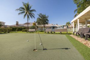 A serene putting green surrounded by palm trees at a resort.