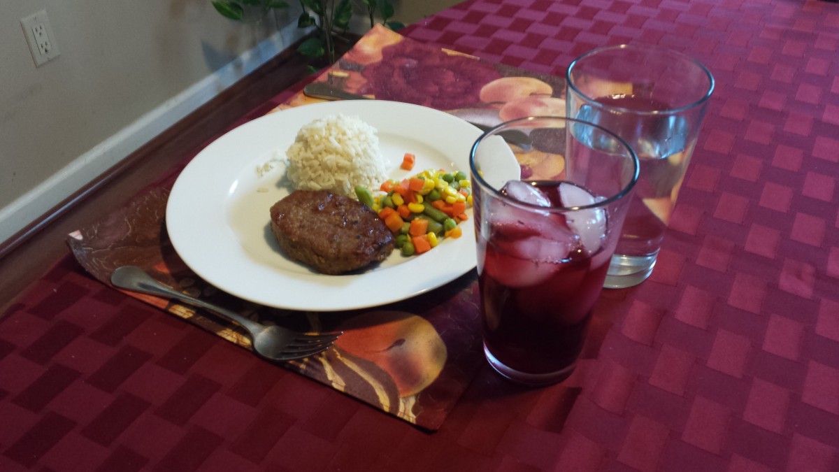A delicious meal served with steak, rice, mixed vegetables, and a refreshing drink on a dining table.