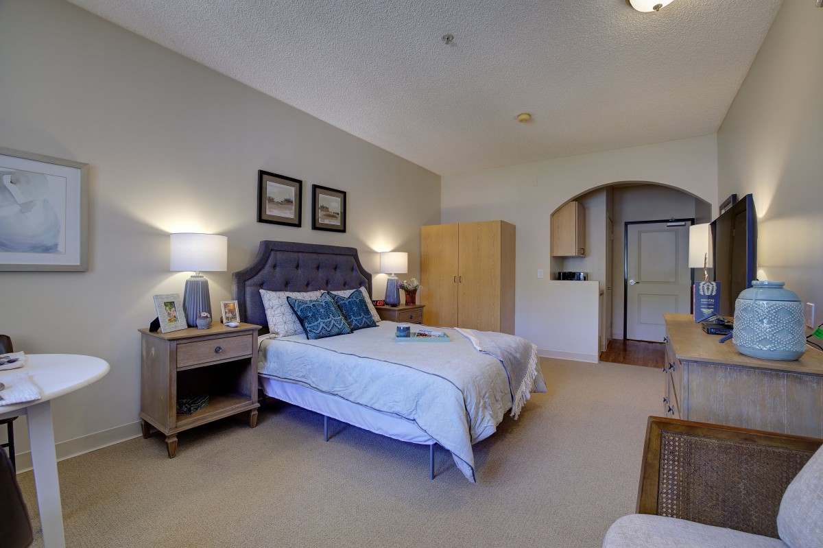 A well-decorated bedroom with a cozy bed, nightstands, lamps, and a wardrobe.