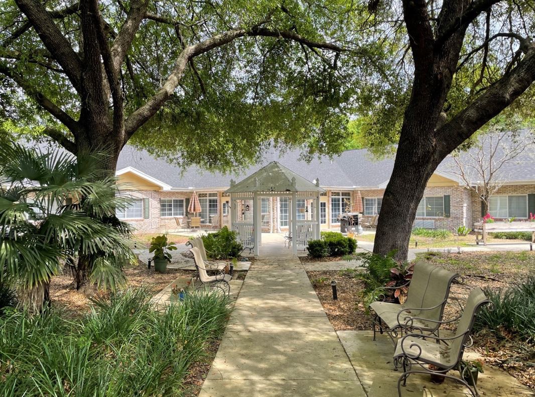 A tranquil house surrounded by lush greenery, featuring a pathway and outdoor seating.