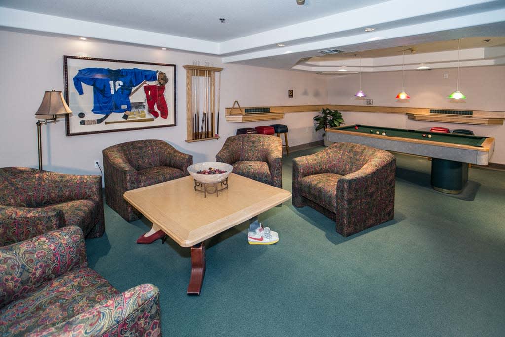 A comfortable lounge area with armchairs and a central table, featuring modern artwork on the wall.