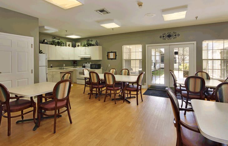 A bright and spacious kitchen dining area with several tables and chairs.