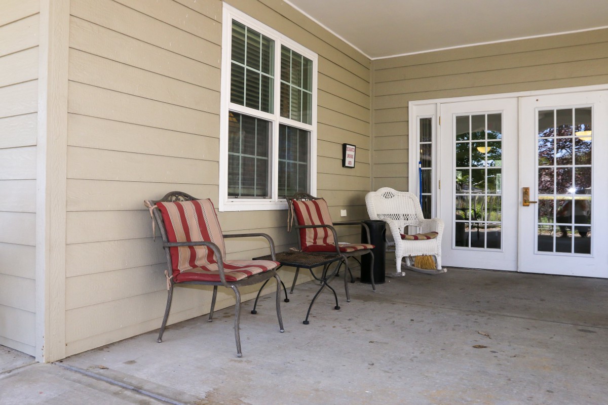 A cozy porch with outdoor seating and a window overlooking the area.