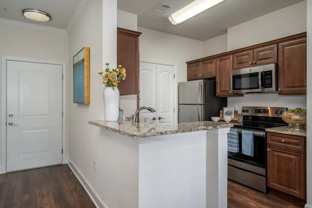 A modern kitchen area with stainless steel appliances and wooden cabinets.