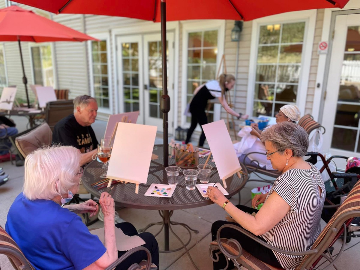A group of seniors enjoying an outdoor painting session on a patio.