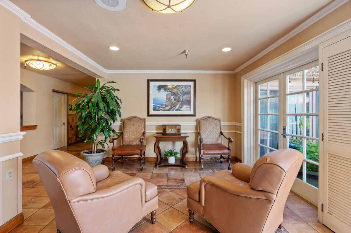 A cozy lobby with comfortable chairs and a central table, decorated with plants and artwork.