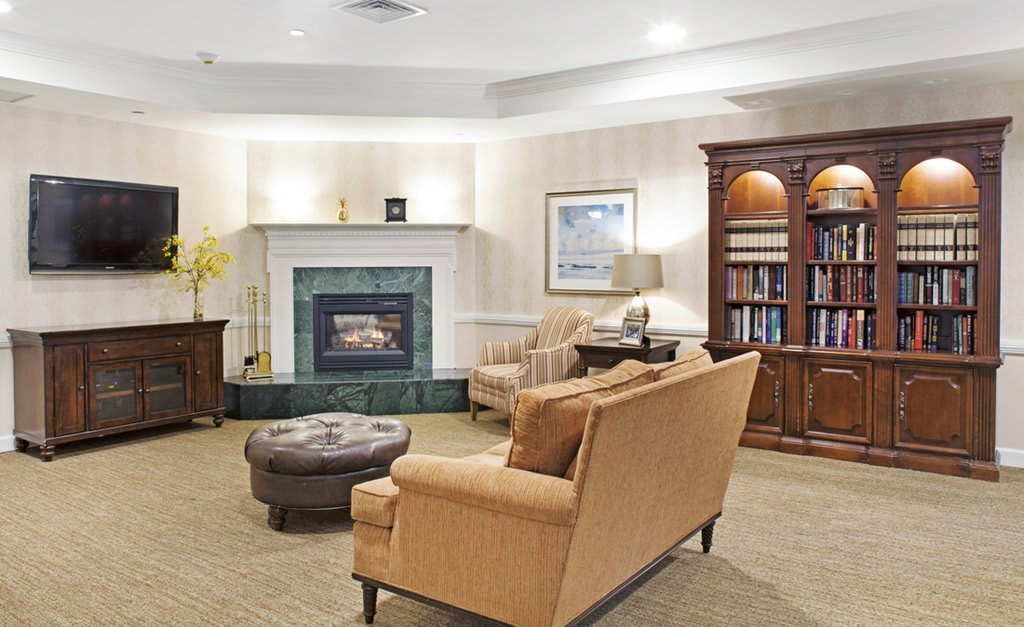 A cozy living room with a fireplace, sofa, armchair, and bookshelf.