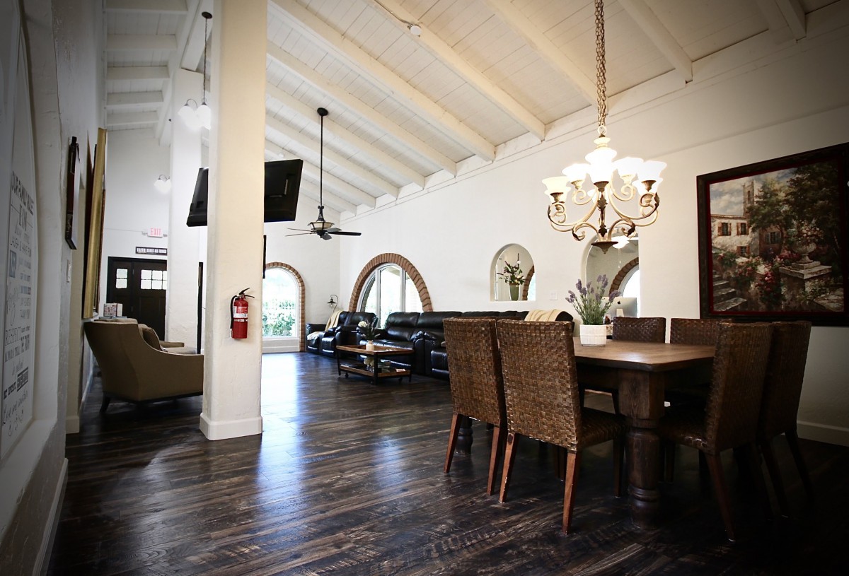 A spacious living and dining area with high ceilings, featuring a wooden floor and elegant chandelier.