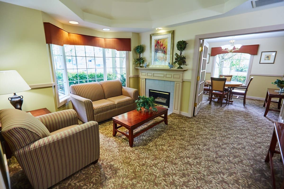 A cozy living room with a sofa, armchair, and fireplace.