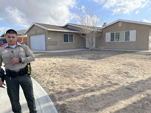 A law enforcement officer standing outside a residential home.