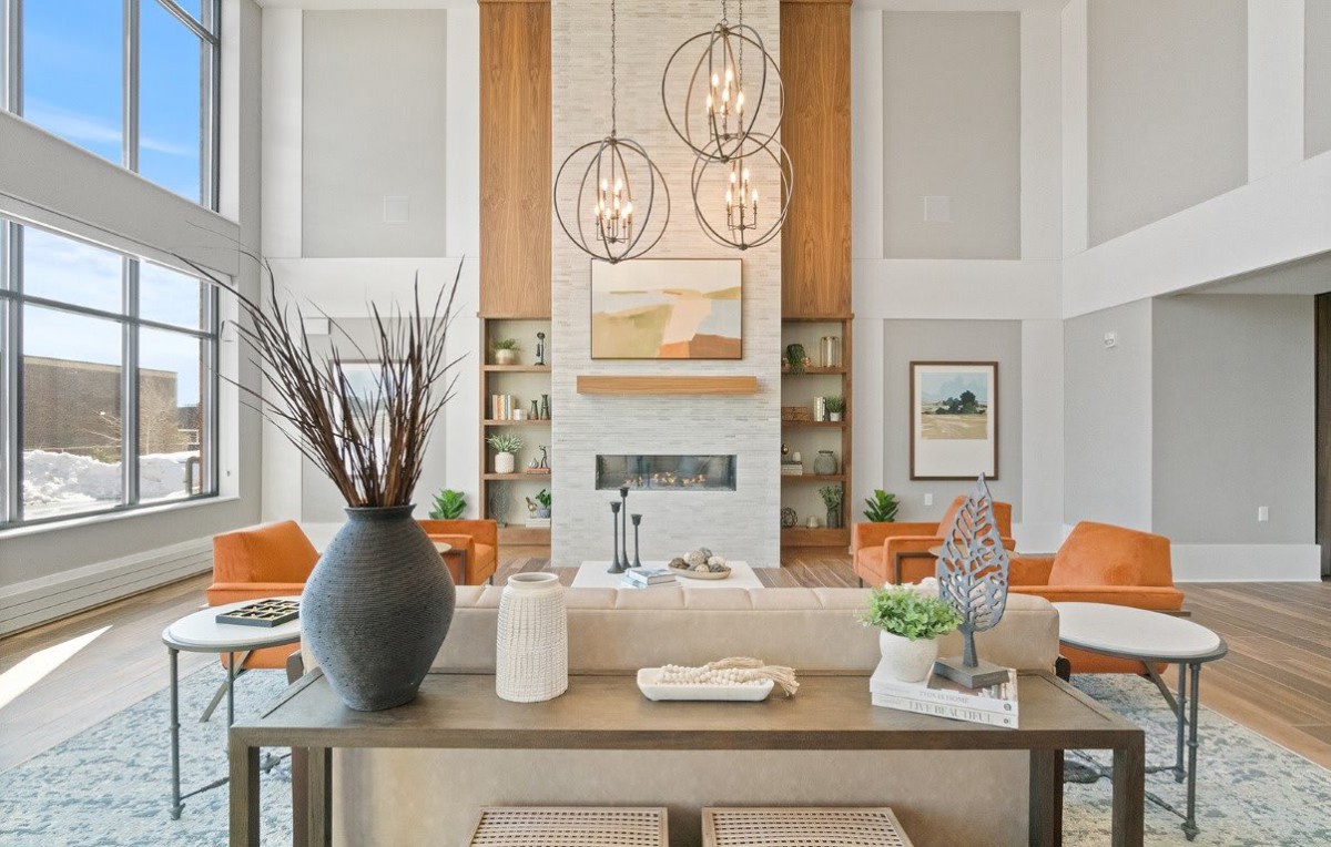 A modern living room with a stylish design featuring hanging chandeliers, artwork, and elegant furniture.