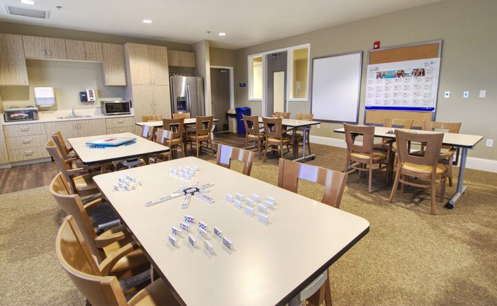 A modern classroom setup with tables, chairs, and a whiteboard for educational activities.