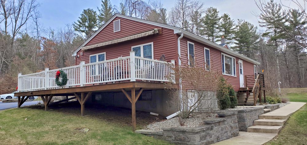 A quaint wooden cabin with a large deck set in a wooded area.