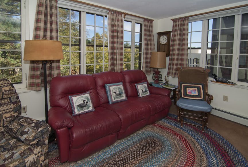 A cozy living room featuring a red sofa, plaid curtains, and decorative pillows.