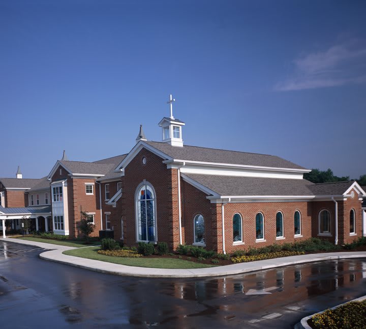 A brick church with a prominent steeple against a clear blue sky.