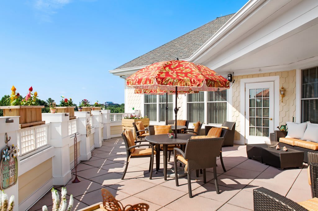 A sunny outdoor patio with a table, chairs, and an umbrella.