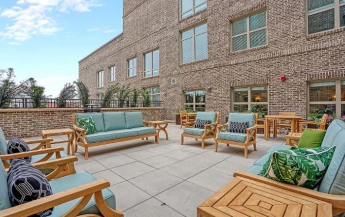 A spacious outdoor patio with comfortable seating arrangements against a brick building backdrop.