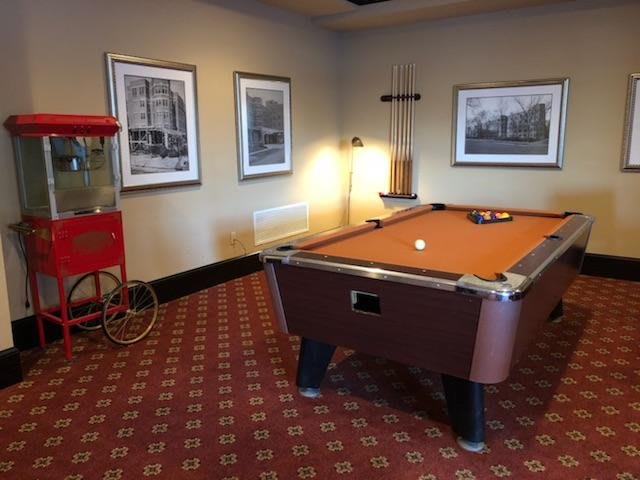 A cozy game room featuring a pool table and a vintage popcorn machine, decorated with framed artwork.