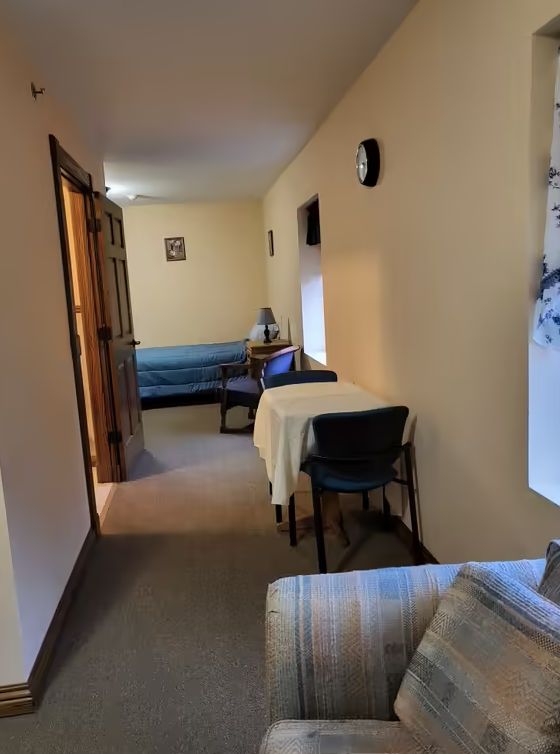 A cozy hallway with a table and chairs, leading to a room with a sofa.